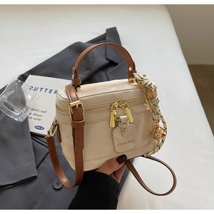 Gros plan sur le sac boîte en cuir verni beige avec double fermeture éclair