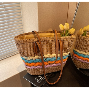Detail of straw woven bucket bag featuring colorful wave patterns and leather straps