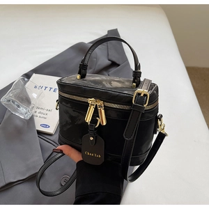 Détail d'un sac boîte noir avec fermetures dorées et étiquette sur une veste de costume