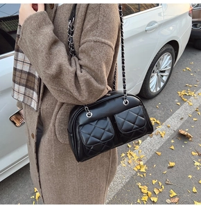 Detail of vintage black quilted chain bag with double front pockets in outdoor setting