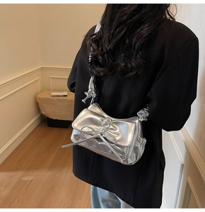 Detail of silver metallic handbag with ruched texture and a decorative bow design