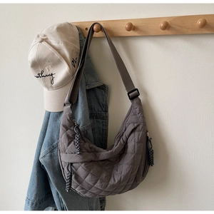 Detail of dark grey quilted hobo bag featuring woven rope puller on wooden hook