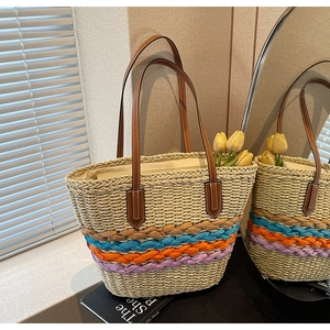 Detail of colorful woven stripes and leather handles on a beige straw tote bag