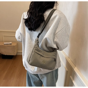 Dettaglio della borsa a tracolla in nylon grigio-verde con cinturino e logo
