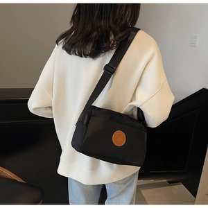 Vue détaillée d'un sac bandoulière en nylon noir avec sangle ajustable porté par un mannequin