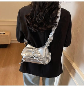 Detail of silver metallic shoulder bag featuring a chic bow and scrunchie strap design