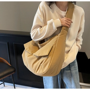 Khaki crescent-shaped padded tote bag shown from a side angle on a model