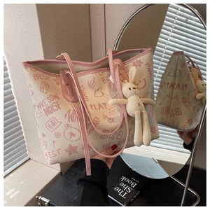 Detail of cream tote bag with pink bear patterns and a cute plush rabbit charm