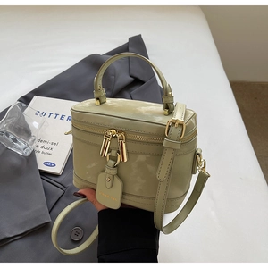 Détail du sac boîte vert pistache avec doubles fermetures dorées et finition cuir brillant