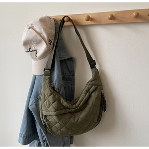 Detail of army green quilted half-moon bag with side zip pocket and adjustable strap