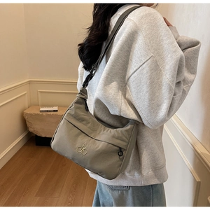 Dettaglio della borsa a mezzaluna in nylon grigio chiaro con tracolla indossata da modella