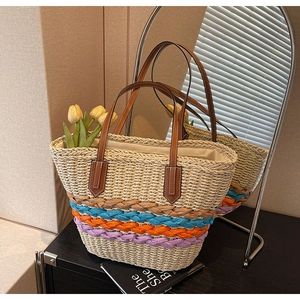 Detailed macro view of woven straw tote bag with colorful braided straps and leather handles