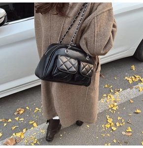 Detailed view of black quilted pillow bag with chain strap and dual front flap pockets
