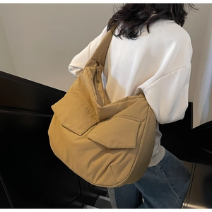 Detail view of khaki crossbody bag featuring large flap pockets and wide strap on model