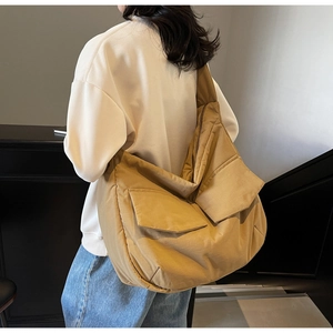 Detail of khaki tote bag showing dual front flap pockets and wide shoulder strap comfort