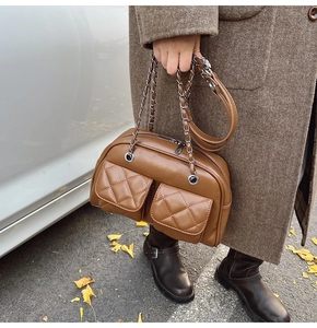 Close-up of caramel quilted pillow bag showing silver chain strap and leather texture