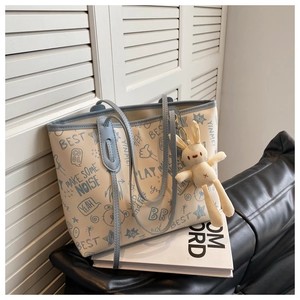 Detail view of stylish graffiti pattern tote bag with blue straps and cute rabbit charm