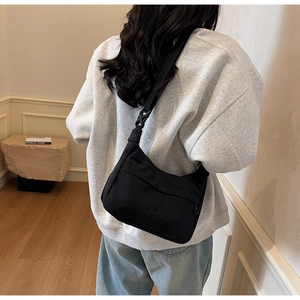 Modella che indossa la borsa hobo nera con tracolla regolabile e logo inciso