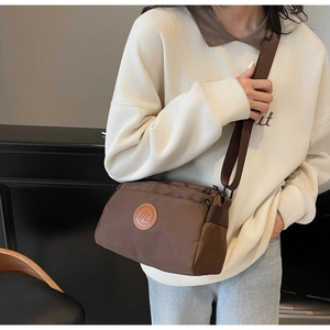 Détail du sac bandoulière en nylon marron foncé avec plusieurs poches zippées et sangle