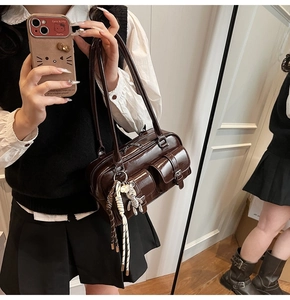 Detail view of glossy brown underarm bag with multi-pockets and decorative charms