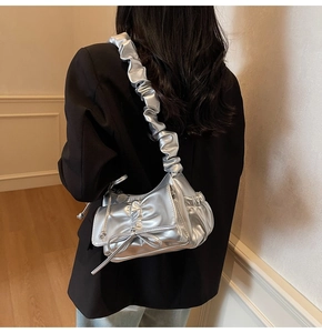 Detail of silver metallic shoulder bag with pleated textures and bow design