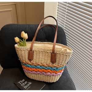 Detail of handcrafted straw tote featuring multicolor woven stripes and leather handles