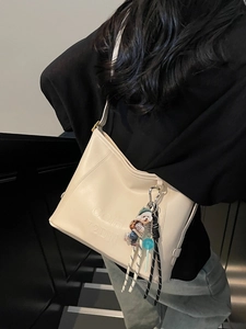 Minimalist cream shoulder bucket bag with debossed lettering and cute bear charm