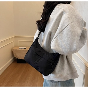 Dettaglio della borsa a mezzaluna in nylon nero minimalista su felpa grigia