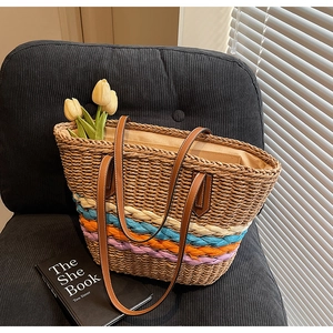 Close-up of handmade straw tote bag with colorful woven stripes and brown leather strap
