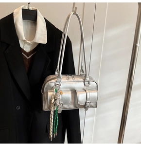 Silver metallic shoulder bag detail showing double flap pockets and cute bear pendant