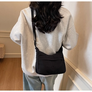 Dettaglio di una borsa a tracolla nera in nylon con tracolla regolabile indossata da modella