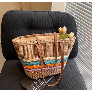 Macro detail of straw woven tote bag featuring colorful braided accents and leather strap