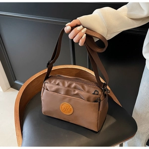Vue détaillée du sac bandoulière en nylon marron avec poches zippées et sangle large