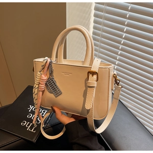 Detailed close-up of cream leather bag featuring an abacus charm and braided rope