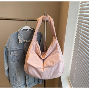 Detail of a pink padded nylon crossbody bag with large front flap pocket and wide strap