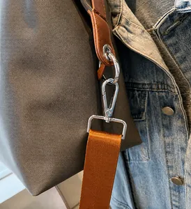 Close-up of silver metal hooks and orange strap on brown nylon crossbody bag