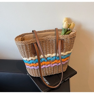 Detail of hand-woven straw tote bag with multi-color wave patterns and leather straps