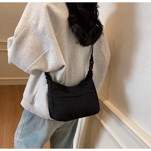 Dettaglio della borsa a tracolla in nylon nero con logo minimalista e tracolla regolabile