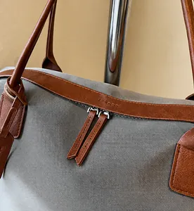 Detailed macro view of smooth dual zippers and brown leather trim on the grey nylon tote