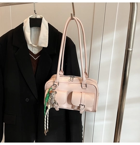 Close-up of pink glossy underarm bag with multi-pockets and a cute metal bear charm