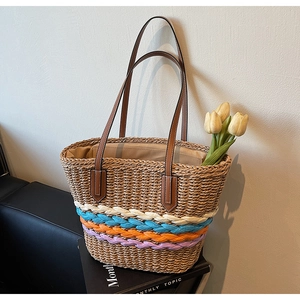 Detail of woven straw tote bag featuring colorful stripes and long brown handles