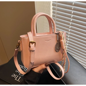 Pink leather handbag detail featuring woven cord charm and metal racket accessory