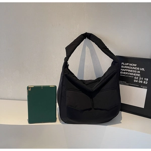 Detail of black nylon tote bag with large double front pockets and wide shoulder strap