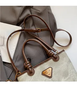 Detail of the adjustable brown leather strap and metal logo on the gray canvas tote bag