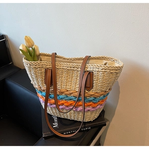 Straw tote bag with colorful accent straps and leather handles on a chair with tulips