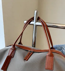 Detail of durable dual metal zippers and faux leather handles on nylon travel tote bag