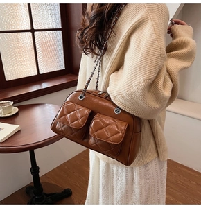 Detail of brown quilted leather pillow bag with silver chain and dual front pockets