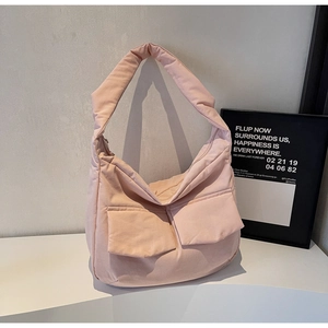Detail of pink quilted tote bag showing two front utility pockets and soft fabric texture