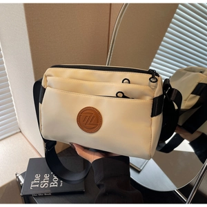 Détail d'un sac bandoulière en nylon blanc crème avec trois poches zippées et sangle large