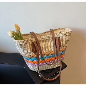 Detail of colorful woven straw tote bag with brown leather straps and summer floral accent